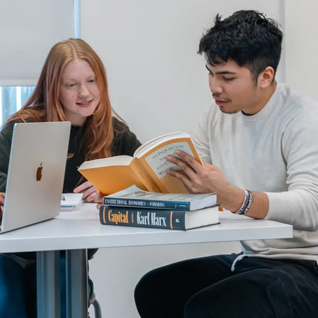 Two students reading an economics book while studying