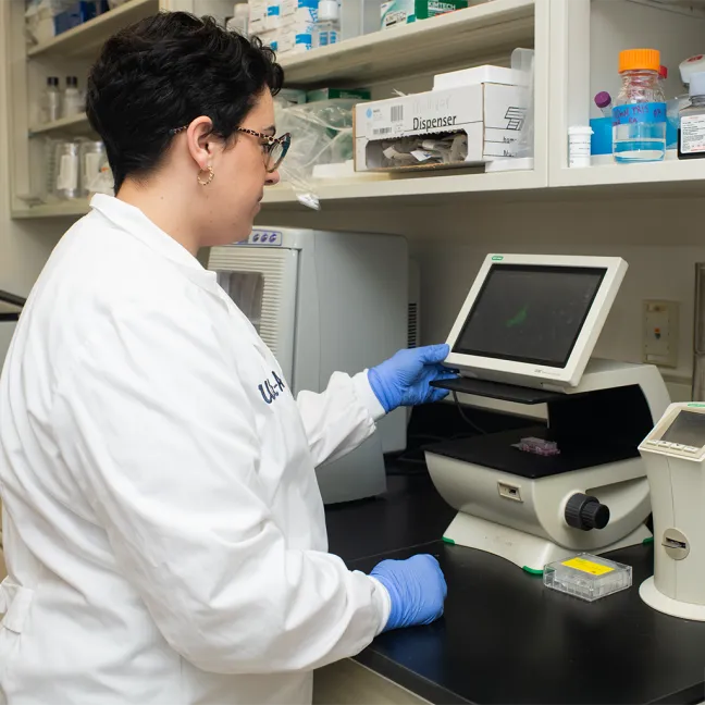 Lab professional using a touchscreen digital microscope imaging system to analyze specimens on the viewing stage.