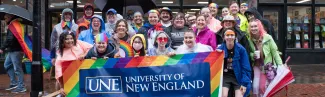 UNE community members gather with a UNE Pride banner in Monument Square in Portland