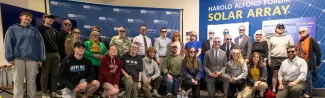 Members of UNE's Community pose in front of a mural inside the Alfond Forum