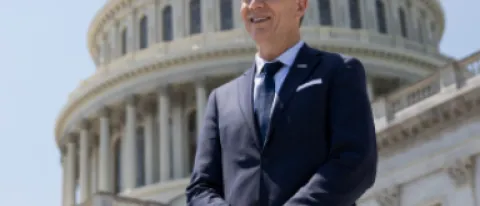President Herbert stands in front of the U.S. Capitol Building