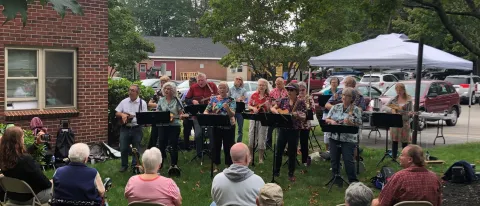 Members of a ukulele band play for seniors outside 