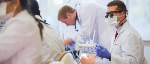A dental student works on a patient simulator