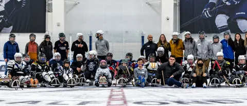 A group of PT students and volunteers/participants from Maine Adaptive post after a sled hockey demonstration at the Harold Alfond Forum