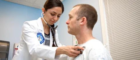 A UNE medical student listens to the heartbeat of an older adult during a health screening