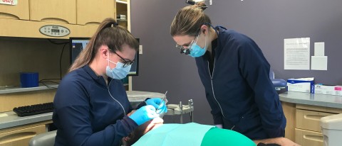 UNE student Kailee Williams works on a patient as Dr. Audra Boynton looks on
