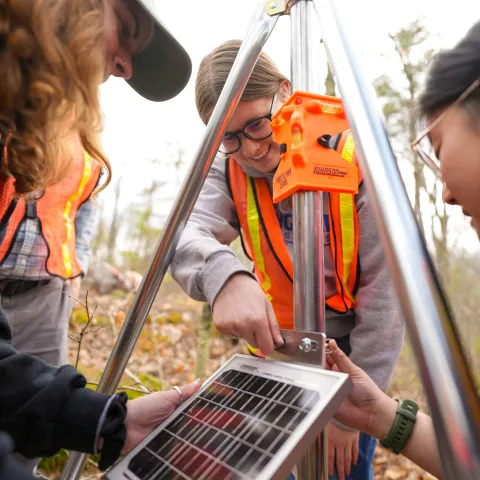 UNE students assemble components of a weather station in UNE's research forest